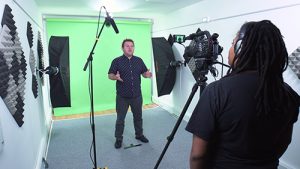 green screen studio filming vlog in a video production studio with cameraman